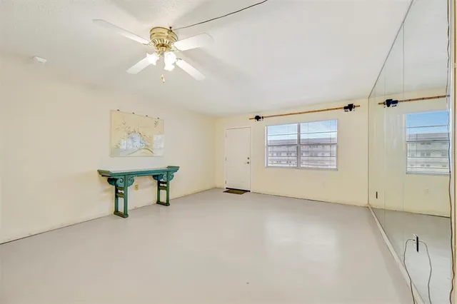 an empty room with windows and ceiling fan
