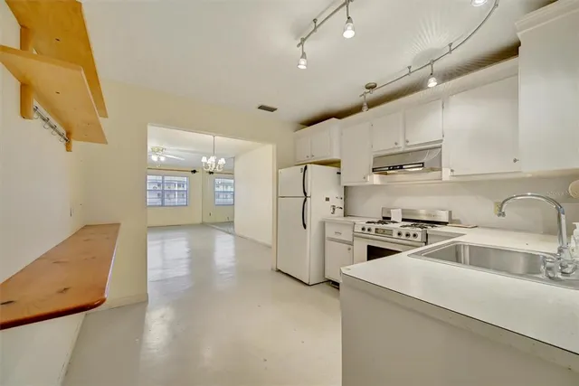 a kitchen with refrigerator a sink and a stove top oven with white cabinets