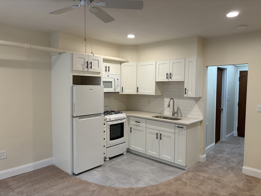 27 Stearns Road, Unit 8 Brookline, MA 02446 - Photo 3 of 9 a kitchen with kitchen island a white cabinets and refrigerator