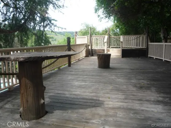 a view of a wooden deck with chairs and large trees