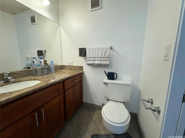 a bathroom with a granite countertop toilet sink and mirror
