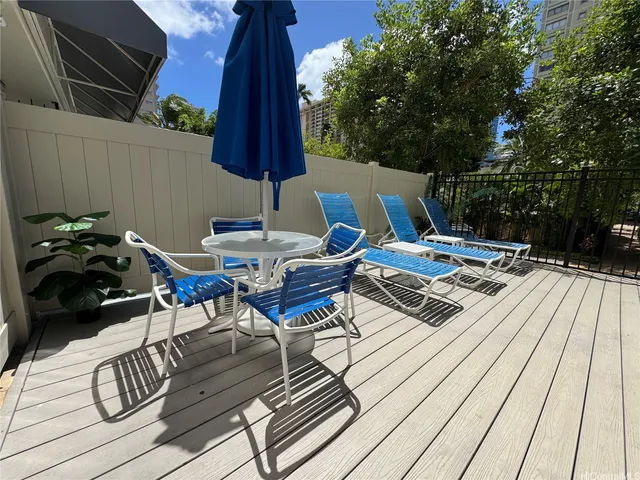 a view of a patio with table and chairs and couches with wooden floor and fence