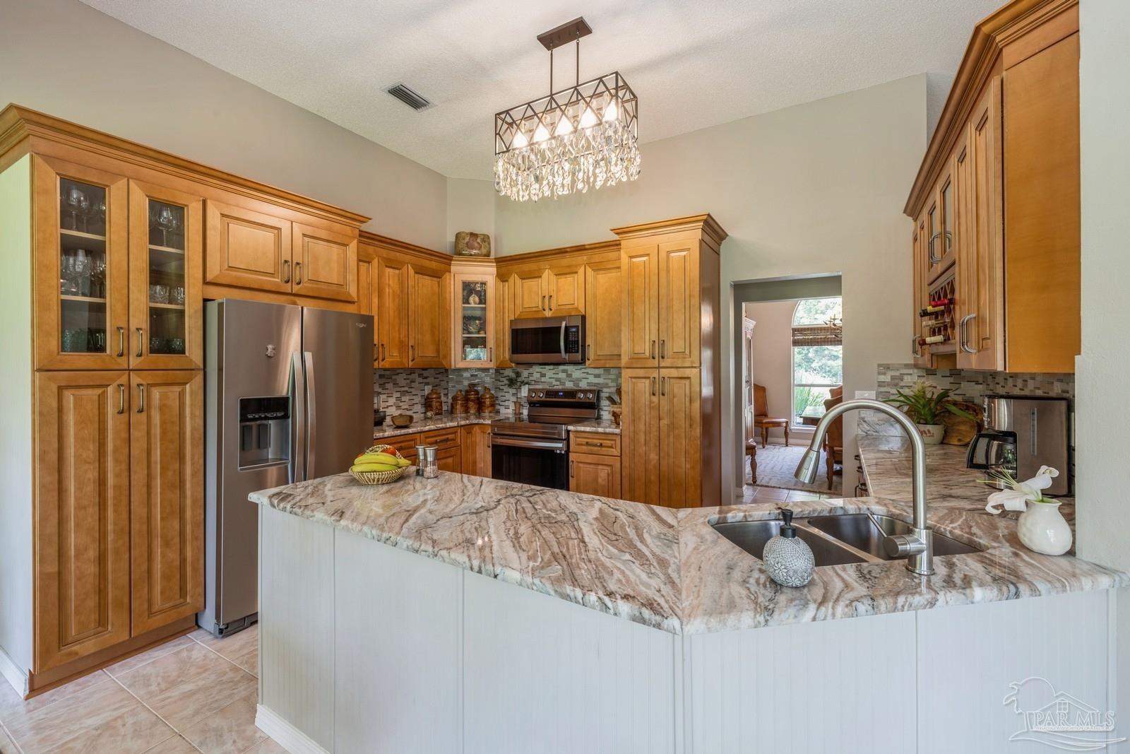 2808 P.G.A Boulevard Navarre, FL 32566 - Photo 17 of 54 a kitchen with stainless steel appliances granite countertop a sink refrigerator and cabinets