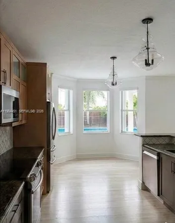 a kitchen with stainless steel appliances a stove a sink a refrigerator wooden floor and cabinets