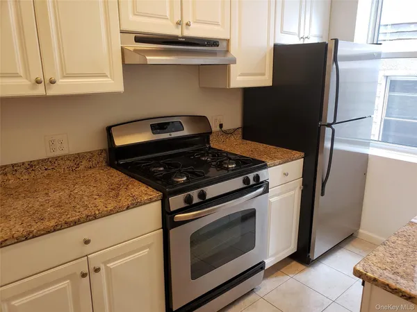 a kitchen with stainless steel appliances granite countertop white cabinets and a stove