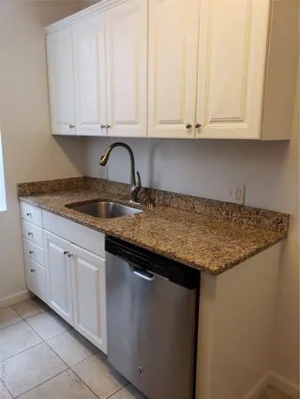 a kitchen with granite countertop white cabinets and a sink