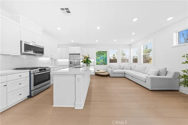 a large white kitchen with a large window and stainless steel appliances