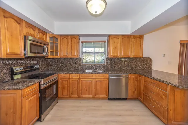 a kitchen with stainless steel appliances granite countertop a stove a sink and a microwave