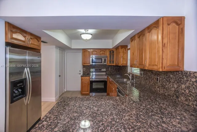 a kitchen with stainless steel appliances granite countertop a refrigerator a stove and a sink