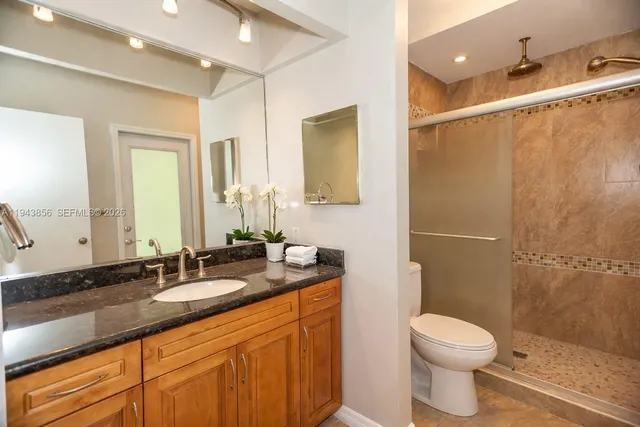 a bathroom with a granite countertop sink a toilet and shower