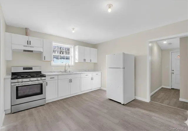 a kitchen with stainless steel appliances white cabinets and wooden floor