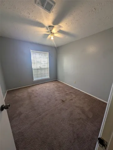 an empty room with windows and fan