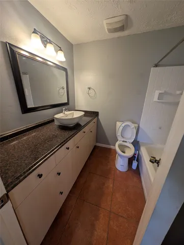 a bathroom with a granite countertop toilet sink and mirror