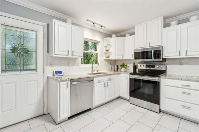 a kitchen with granite countertop white cabinets stainless steel appliances and a window