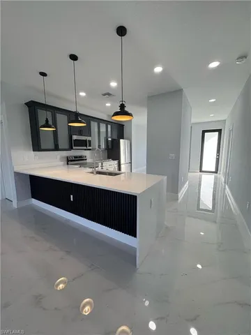 a large kitchen with kitchen island a sink stainless steel appliances and cabinets