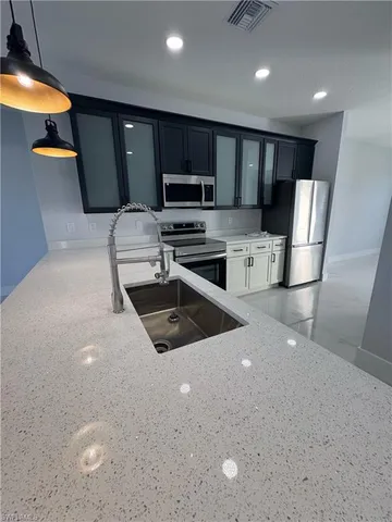 a kitchen with stainless steel appliances a stove a sink a microwave a refrigerator and cabinets