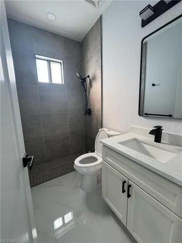 a bathroom with a granite countertop sink a toilet and a mirror
