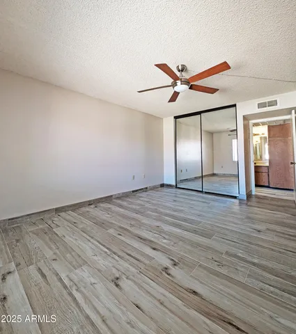 an empty room with wooden floor and fan