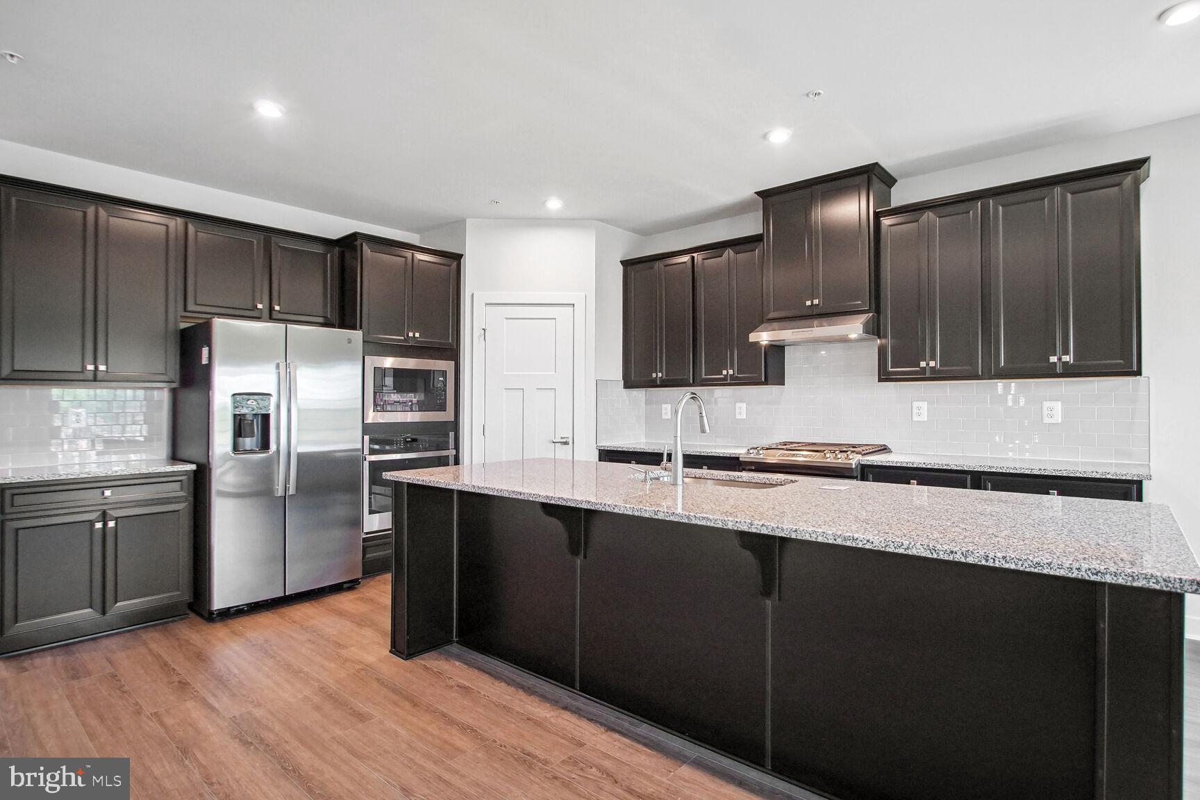 a large kitchen with stainless steel appliances wooden cabinets a refrigerator and a sink