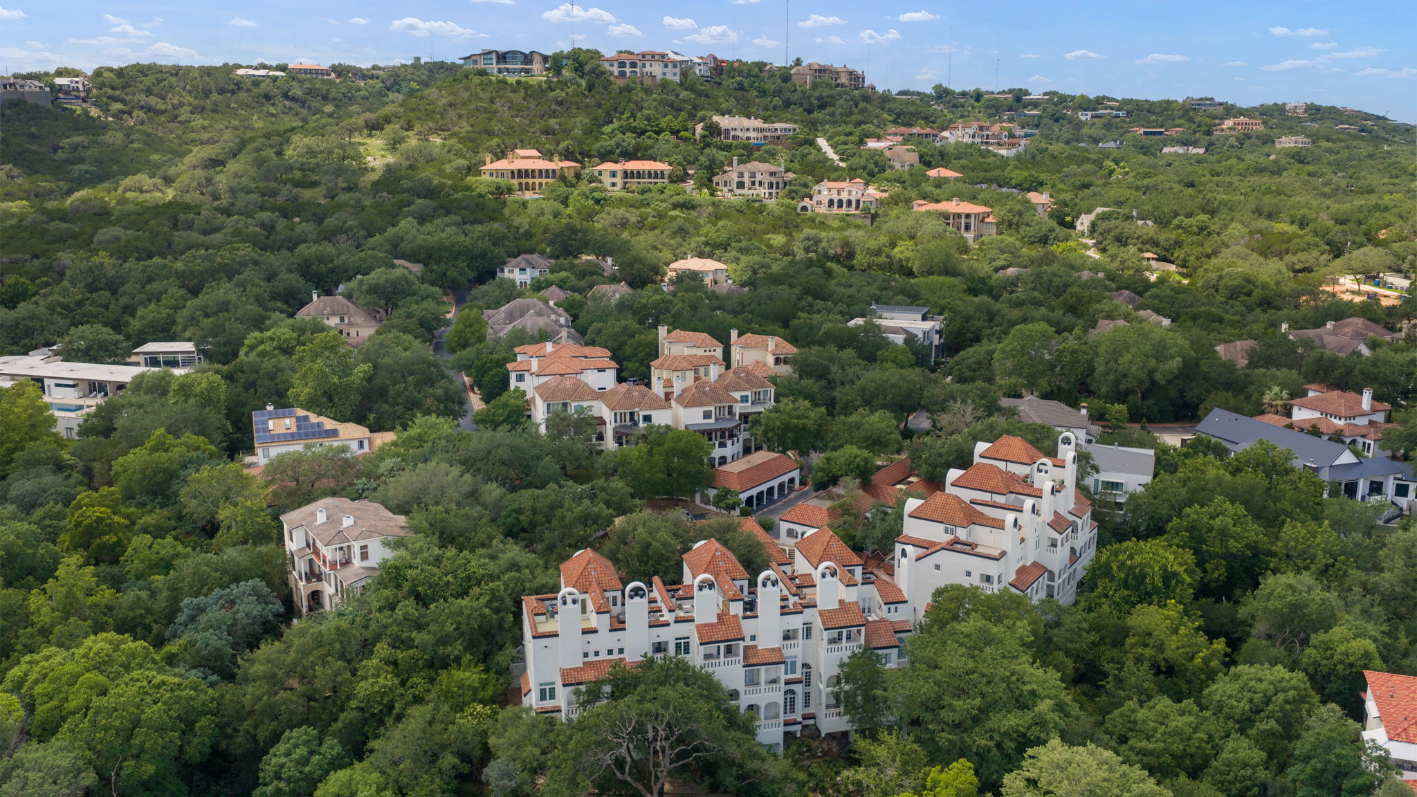 1910 Rue De St Tropez, Unit 6 Austin, TX 78746 - Photo 37 of 37 An aerial panorama reveals a picturesque hillside community nestled among verdant trees and Mediterranean-inspired architecture.