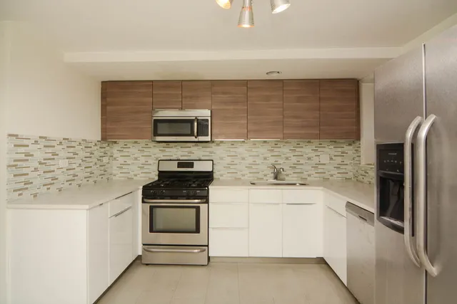 a kitchen with stainless steel appliances kitchen island granite countertop a stove and a refrigerator