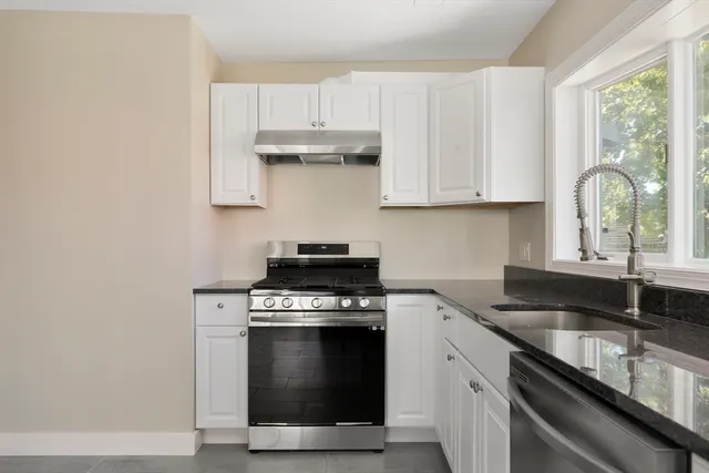 a kitchen with granite countertop white cabinets and appliances