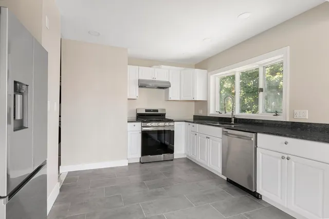 a kitchen with granite countertop white cabinets and white appliances