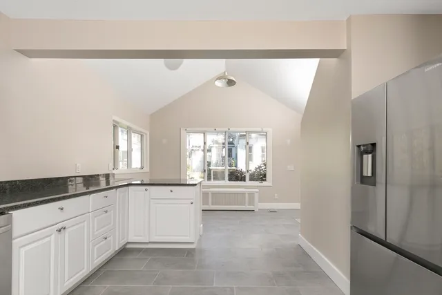 a large white kitchen with granite countertop a sink and cabinets