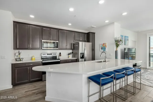 a kitchen with stainless steel appliances a stove a sink a microwave a refrigerator and cabinets