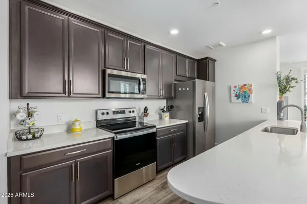 a kitchen with stainless steel appliances a sink a stove a refrigerator cabinets and a counter top space