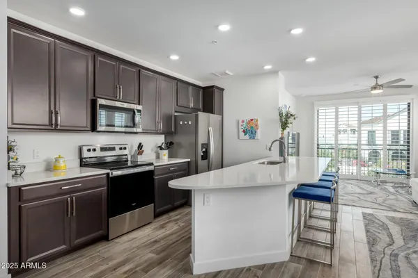 a large kitchen with stainless steel appliances granite countertop a stove a sink dishwasher a microwave oven and a refrigerator with wooden floor