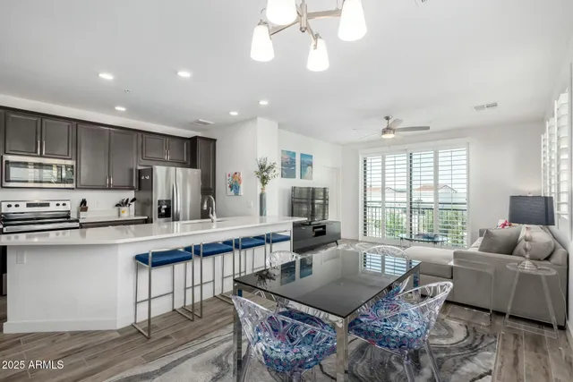 a large kitchen with stainless steel appliances granite countertop a stove a sink a dining table and chairs with wooden floor