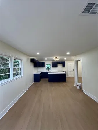 an empty room with furniture and kitchen view