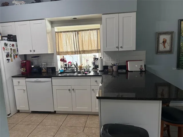 a kitchen with stainless steel appliances granite countertop a stove a sink and white cabinets