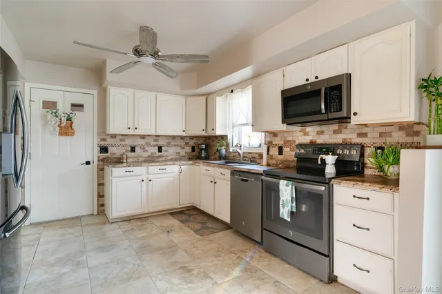 a kitchen with granite countertop a sink stainless steel appliances and white cabinets