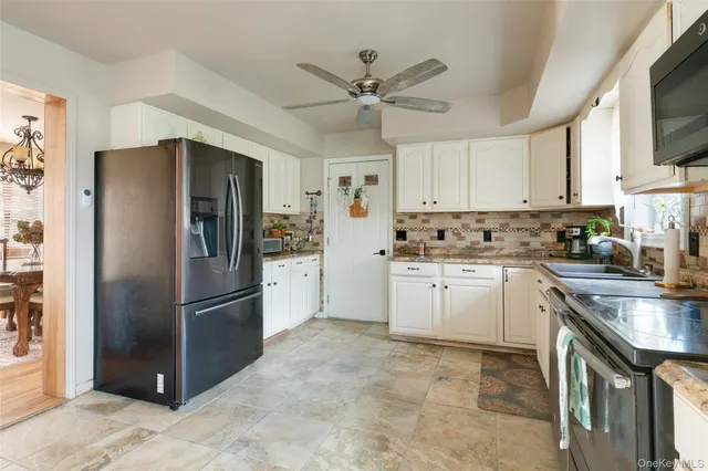 a kitchen with stainless steel appliances granite countertop a refrigerator a sink a stove and white cabinets