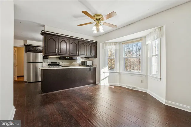 a kitchen with stainless steel appliances kitchen island granite countertop a stove a sink a refrigerator cabinets and wooden floor