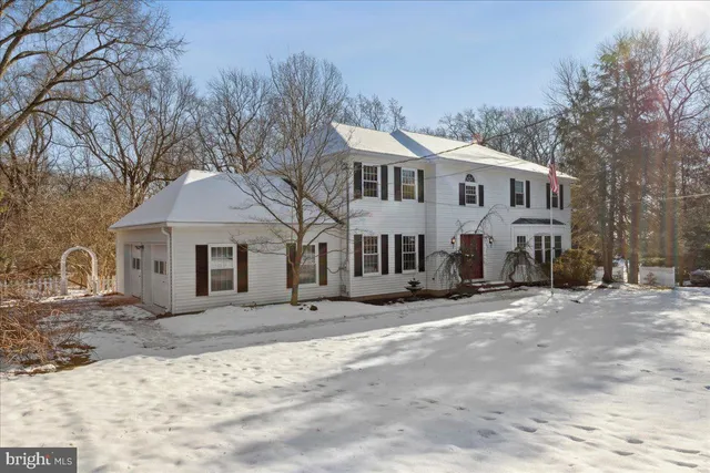 a view of a white house with a large tree next to a yard