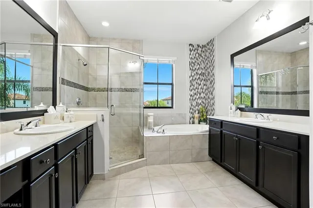 a bathroom with a bathtub double vanity sink and a large mirror