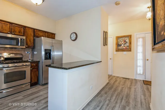 a kitchen with stainless steel appliances granite countertop a refrigerator and a stove top oven
