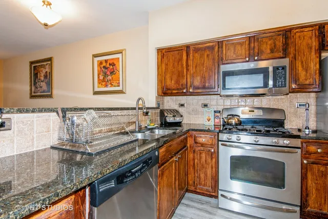a kitchen with granite countertop a stove top oven a sink and dishwasher wooden cabinets with granite countertops