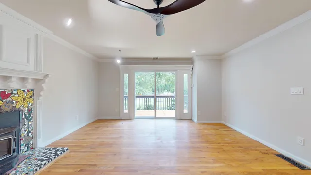 a view of empty room with wooden floor and fan