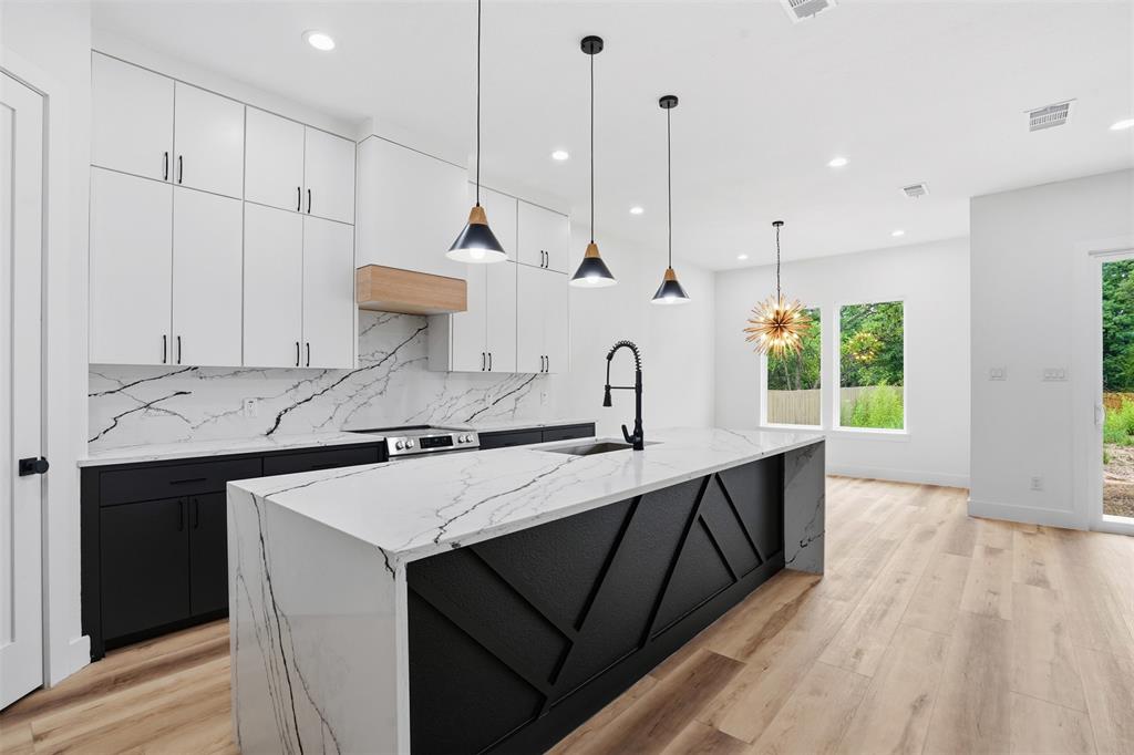 1111 Riverwood Road Dallas, TX 75217 - Photo 18 of 40 Kitchen featuring a waterfall island with black paneled base, white countertops with prominent veining, and a matte black faucet