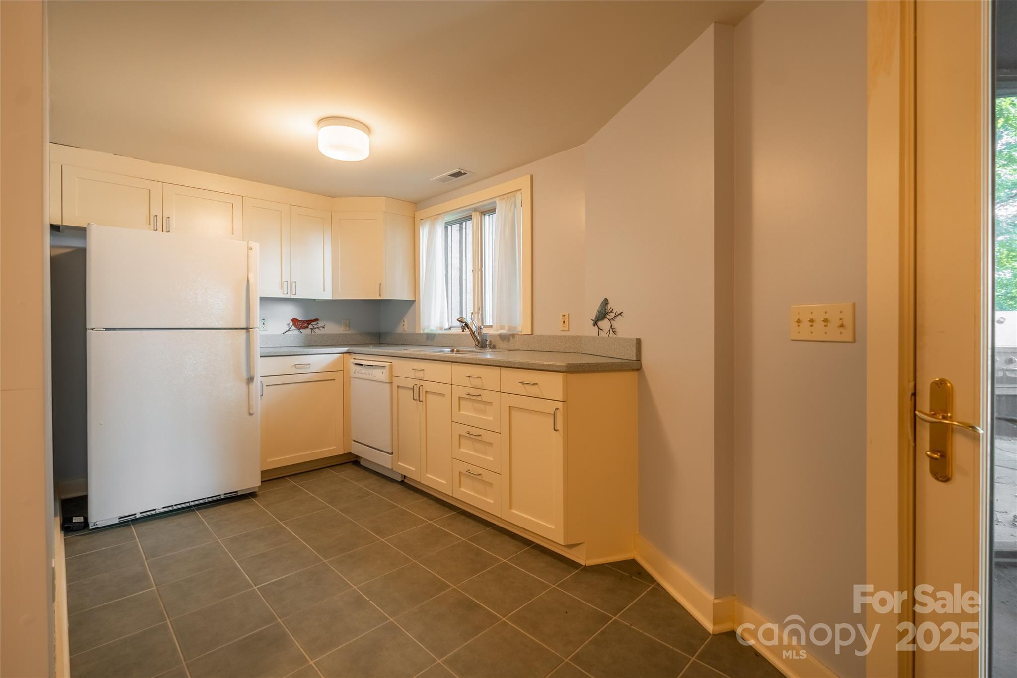 130 Piney Rdg Lane Saluda, NC 28773 - Photo 36 of 48 a kitchen with a sink a refrigerator a window and white cabinets