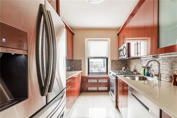 a kitchen with stainless steel appliances granite countertop a refrigerator a sink and white cabinets with wooden floor