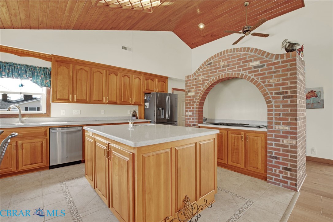 9093 Stump Point Road Hayes, VA 23072 - Photo 15 of 40 Kitchen featuring a central island with a solid surface countertop, light wood cabinetry, a vaulted wood-paneled ceiling, a brick arched alcove, and tile flooring with decorative inlay