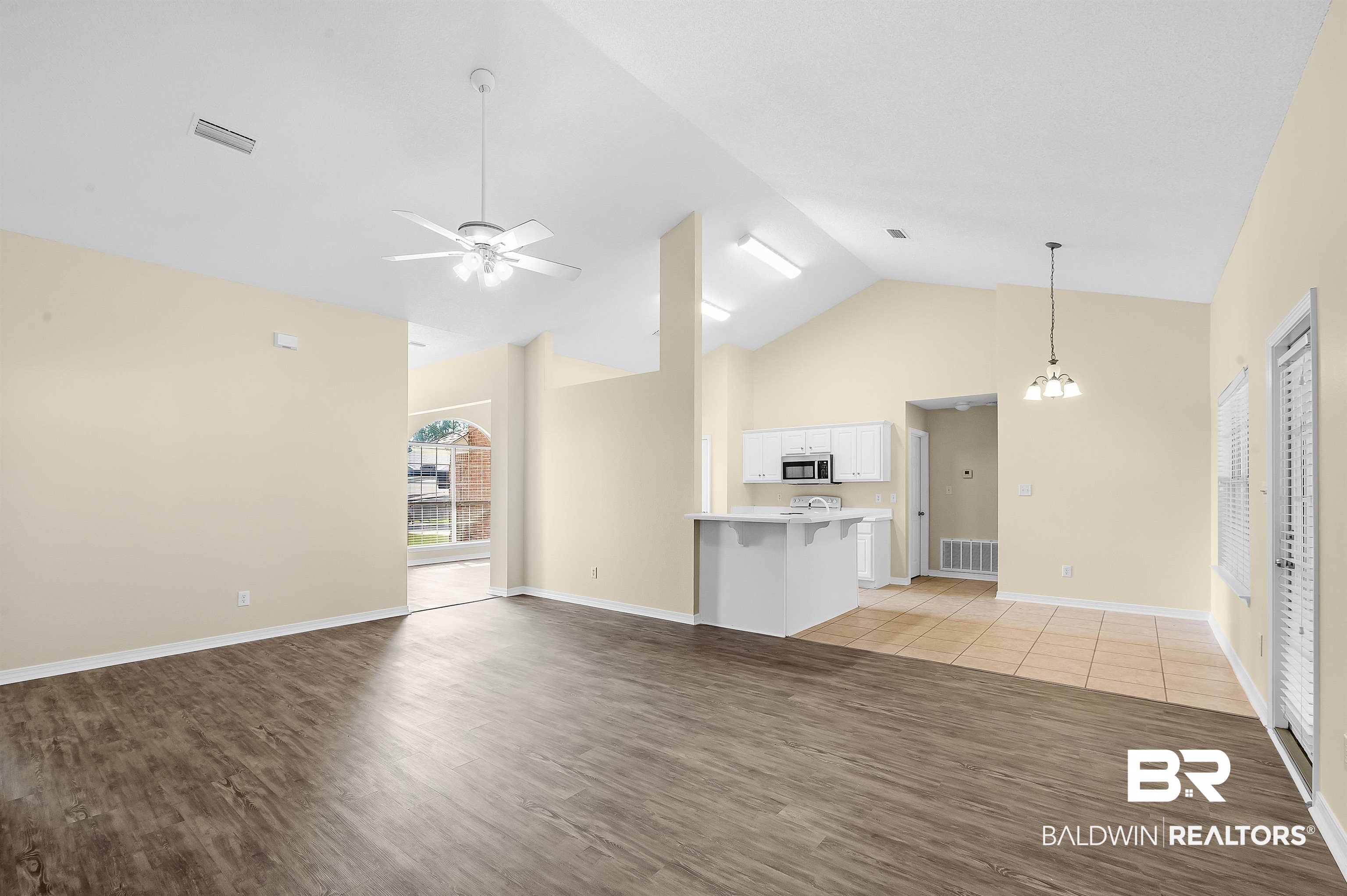 12443 Venice Boulevard Foley, AL 36535 - Photo 25 of 59 Unfurnished living room featuring ceiling fan with notable chandelier, high vaulted ceiling, and light hardwood / wood-style floors