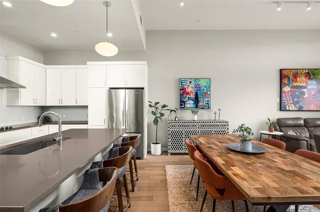 a kitchen with stainless steel appliances granite countertop a dining table chairs refrigerator and sink