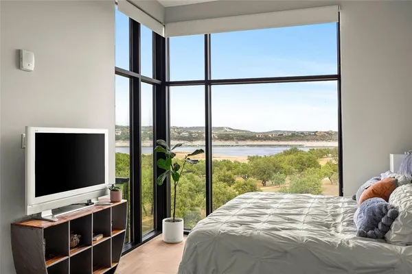 a bedroom with a bed and a flat tv screen next to a window