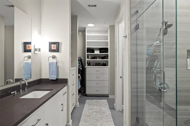 a bathroom with a granite countertop sink two mirror and shower